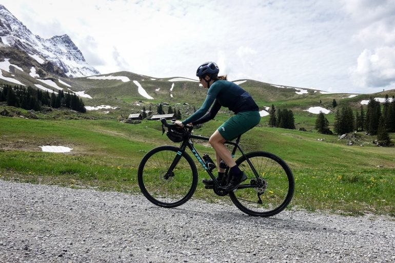 Frau mit Gravelbike auf Schotterstrasse